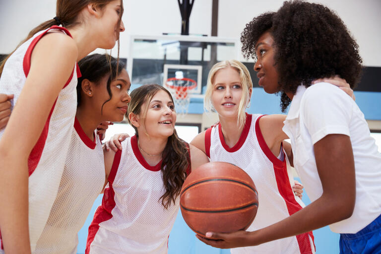 Female High School Basketball Players In Huddle Having Team Talk With Coach