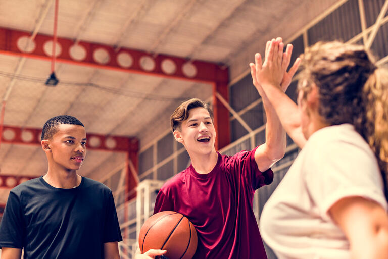 Group of teenager friends on a basketball court giving each other a high five