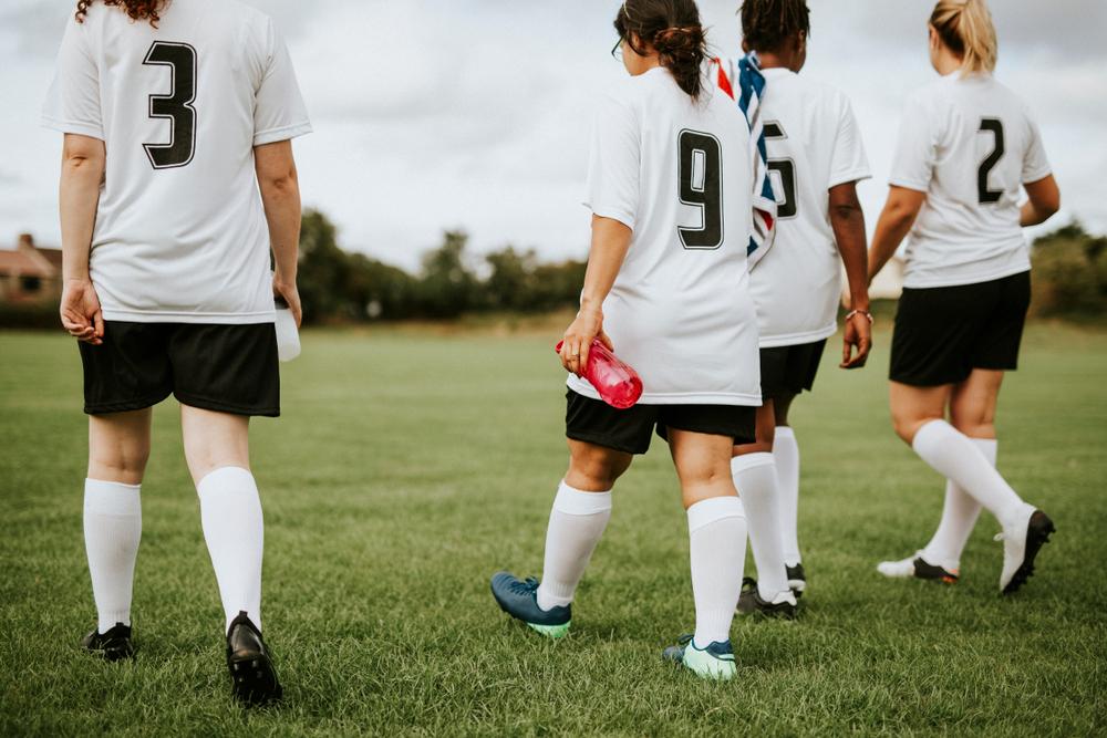 Junior female football players walking on a field