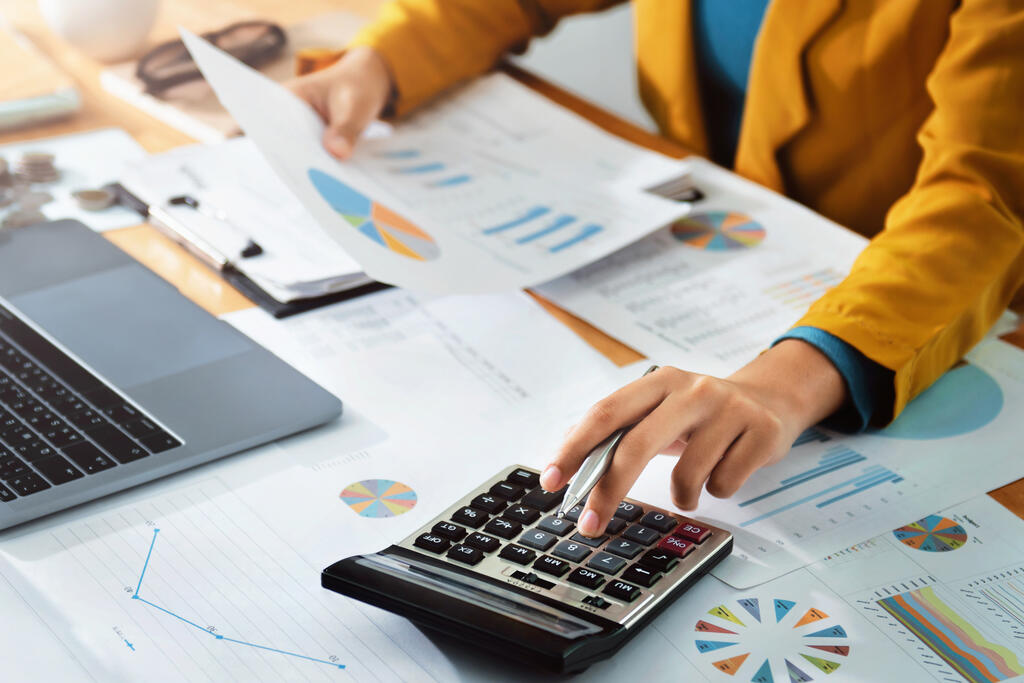 Woman accountant use calculator and computer with holding pen on