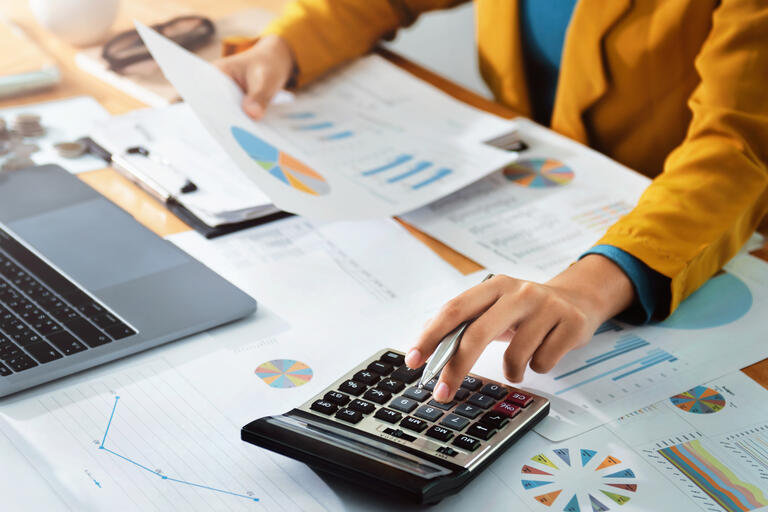 Woman accountant use calculator and computer with holding pen on