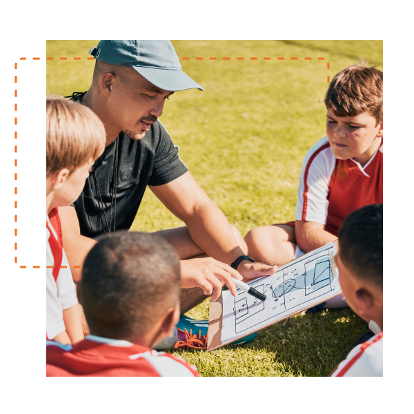 Soccer coach with clipboard on field with soccer team